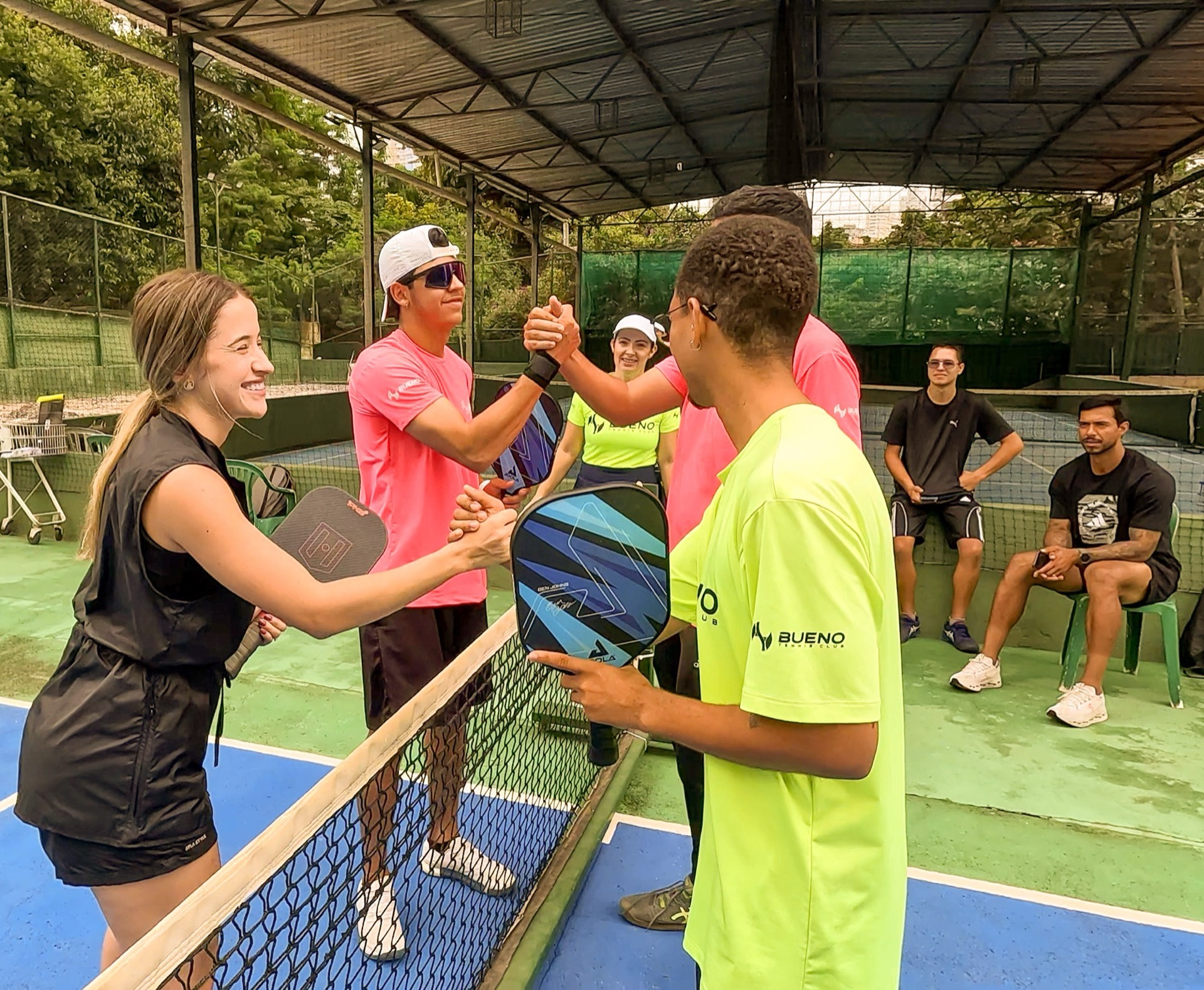 Cumprimento na rede ao fim de jogo de pickleball, seis jogadores na quadra da BTC.