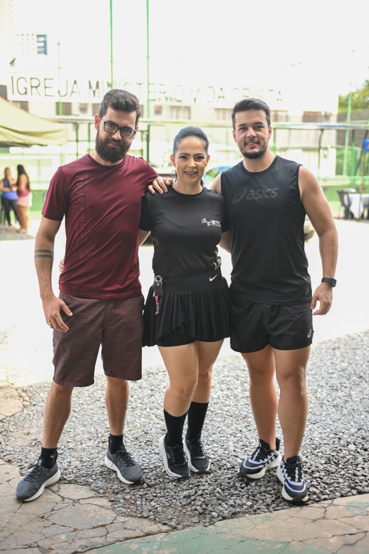 Trio em pé na BTC, Ivan, Marina e mais um, com o letreiro do prédio vizinho ao fundo.